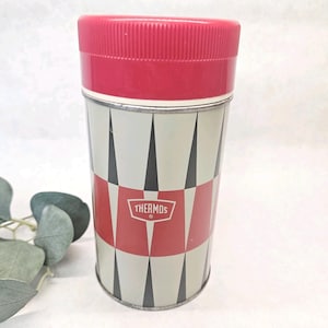 May include: Vintage Thermos brand insulated bottle with a red lid and a geometric pattern in red, black, and cream. The Thermos logo is displayed on the front. A classic container for keeping beverages hot or cold.