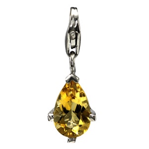Può includere: Un ciondolo d'argento con una pietra preziosa di topazio a forma di pera. La pietra preziosa è di colore giallo chiaro.