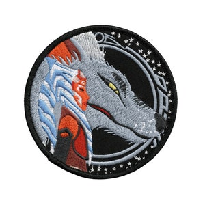 以下が含まれることがあります： グレーのオオカミと青とオレンジの髪をした女性が描かれた刺繍パッチ。黒い背景に円形のデザインが施されています。
