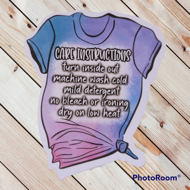 Peut inclure: Un t-shirt tie-dye violet et bleu avec du texte blanc qui dit "CARE INSTRUCTIONS turn inside out machine wash cold mild detergent no bleach or ironing dry on low heat".