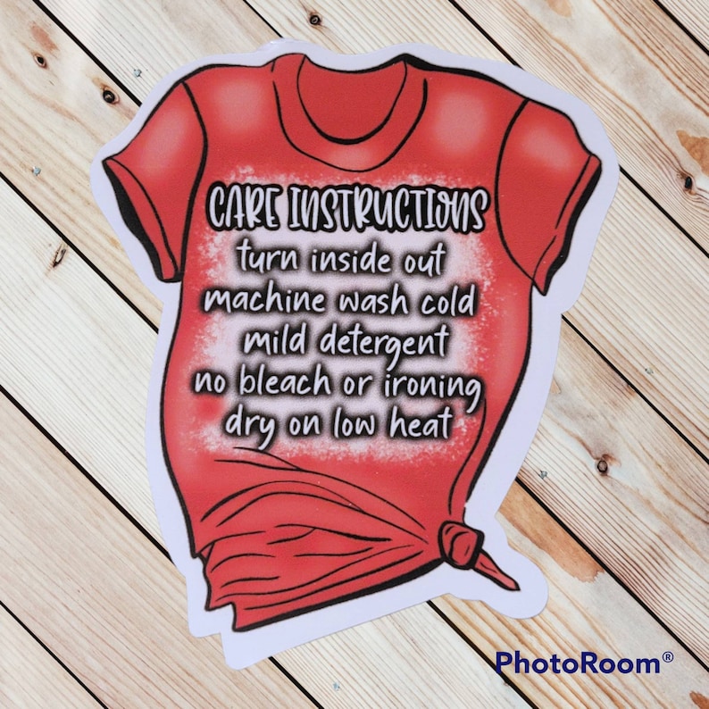 Peut inclure: Un t-shirt rouge avec du texte blanc qui dit "CARE INSTRUCTIONS turn inside out machine wash cold mild detergent no bleach or ironing dry on low heat".
