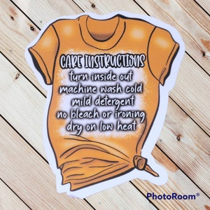 Peut inclure: Un t-shirt jaune avec des instructions d'entretien imprim&eacute;es dessus. Les instructions disent : "Retourner &agrave; l'envers, laver en machine &agrave; froid, d&eacute;tergent doux, pas de javel ni de repassage, s&eacute;cher &agrave; basse temp&eacute;rature."