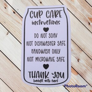 Puede incluir: Una pegatina morada con el texto "CUP CARE instructions" e instrucciones de cuidado para una taza. Las instrucciones dicen "DO NOT SOAK", "NOT DISHWASHER SAFE", "HANDWASH ONLY", "NOT MICROWAVE SAFE" y "THANK YOU handle with care".