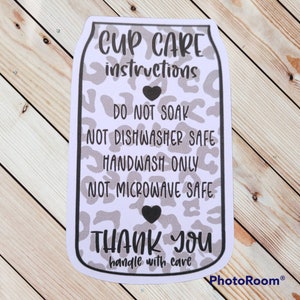 Puede incluir: Pegatina blanca con un dise&ntilde;o de estampado de leopardo blanco y negro. La pegatina tiene texto negro que dice "CUP CARE instructions DO NOT SOAK NOT DISHWASHER SAFE HANDWASH ONLY NOT MICROWAVE SAFE THANK YOU handle with care".