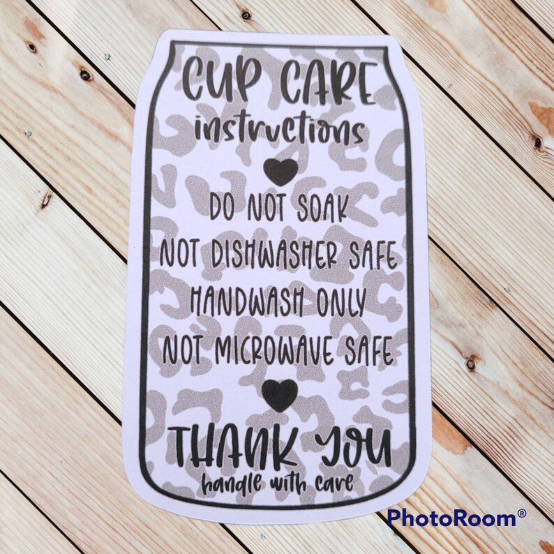 Puede incluir: Pegatina blanca con un dise&ntilde;o de estampado de leopardo blanco y negro. La pegatina tiene texto negro que dice "CUP CARE instructions DO NOT SOAK NOT DISHWASHER SAFE HANDWASH ONLY NOT MICROWAVE SAFE THANK YOU handle with care".