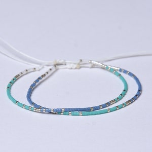 Peut inclure: Deux bracelets en perles avec un cordon blanc. Un bracelet est bleu et l'autre turquoise.