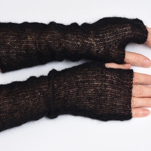 May include: A pair of black fingerless gloves crafted from a fine, sheer, and fuzzy knit material. These arm warmers extend from the knuckles to the mid-forearm, featuring a lightweight, semi-transparent texture with a soft, brushed appearance.