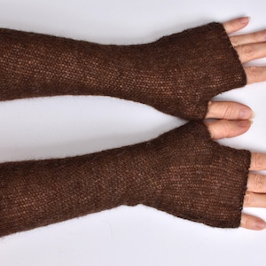 May include: A pair of dark brown fingerless gloves made from a fine, semi-sheer knitted yarn. These arm warmers extend from the knuckles to the mid-forearm, featuring a simple, open-ended design with a dedicated opening for the thumb.