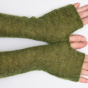 May include: A pair of olive green fingerless gloves crafted from a soft, fuzzy knit material. These arm warmers extend from the knuckles to the mid-forearm, featuring a simple thumb opening and a consistent, textured stitch throughout the design.