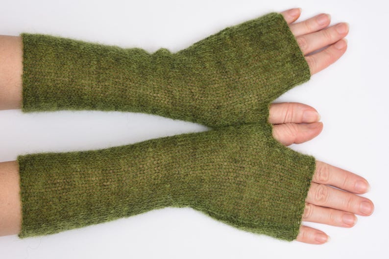 May include: A pair of olive green fingerless gloves crafted from a soft, fuzzy knit material. These arm warmers extend from the knuckles to the mid-forearm, featuring a simple thumb opening and a consistent, textured stitch throughout the design.