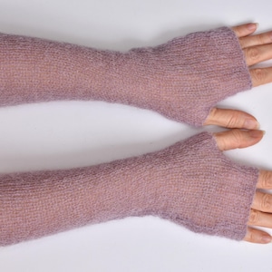 May include: A pair of long, fingerless gloves in a soft, muted mauve color. These arm warmers feature a lightweight, semi-sheer knitted texture that extends from the knuckles up to the mid-forearm, leaving the fingers and thumb exposed.