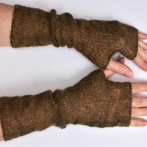 May include: A pair of dark brown fingerless gloves featuring a fine, semi-sheer knit texture. These arm warmers extend from the knuckles to the mid-forearm, showcasing a lightweight, slightly fuzzy yarn construction with a simple thumb opening.