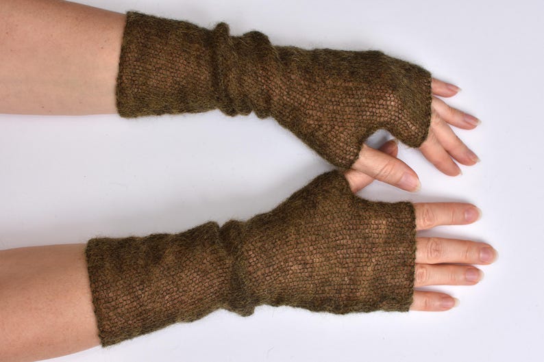 May include: A pair of dark brown fingerless gloves featuring a fine, semi-sheer knit texture. These arm warmers extend from the knuckles to the mid-forearm, showcasing a lightweight, slightly fuzzy yarn construction with a simple thumb opening.