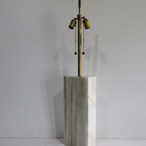 May include: A tall, rectangular lamp with a marble-like base and a brass-colored stem. The lamp has three light sockets and hanging pull chains. The base is a light gray color with darker gray veining.