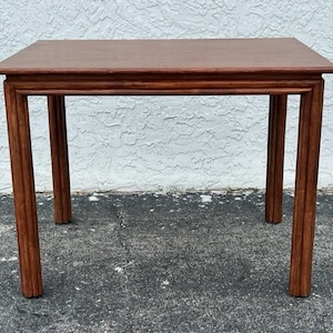 May include: A rectangular wooden table with a dark brown finish. The table has a simple design with four sturdy legs and a slightly raised edge around the tabletop. The table measures approximately 76 cm long, 51 cm wide, and 71 cm high.