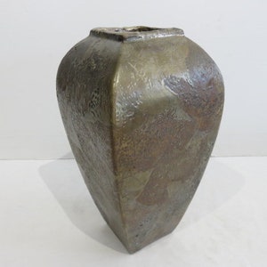 May include: A square-shaped bronze-toned vase with a textured, mottled surface. The vessel features a tapered body that narrows toward the base and a wide, open top with a distinct square rim, showcasing a metallic finish with varied brown hues.