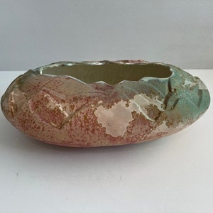 Peut inclure: Un bol ovale en céramique avec un bord texturé et irrégulier ainsi qu'une finition de surface tachetée. L'extérieur présente un mélange de tons terreux, incluant des touches de rose poudré, de terre cuite et de vert sauge, avec un intérieur crème.