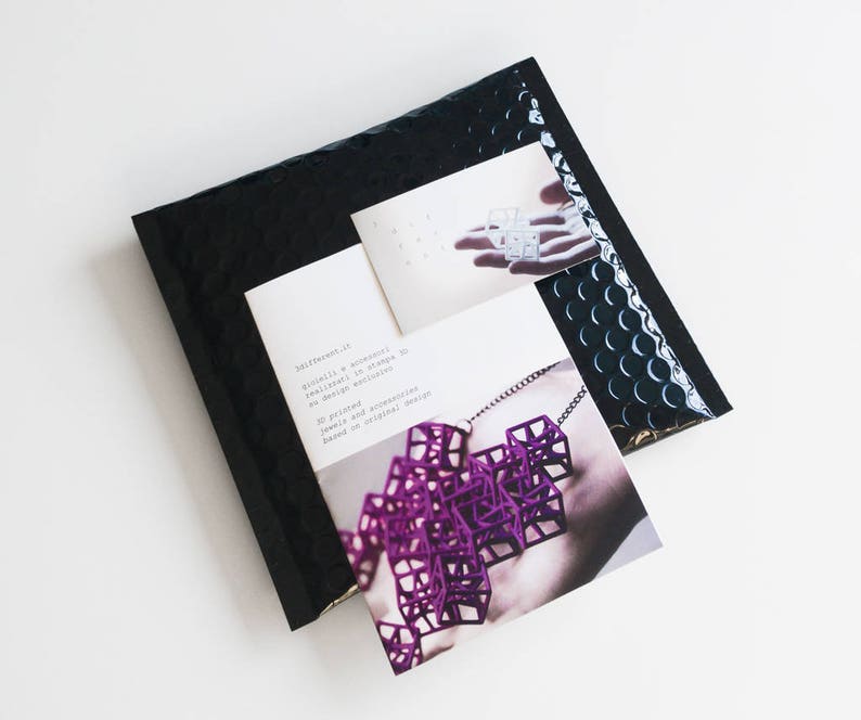 May include: A black bubble mailer with two cards. One card features a purple geometric necklace, and the other shows a similar design. Text on the card reads "3d printed jewels and accessories based on original design."