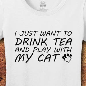 May include: White t-shirt with black text that reads "I just want to drink tea and play with my cat" with a paw print and heart graphic.