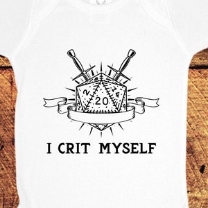 May include: White baby onesie with a black and white illustration of a 20-sided die with two crossed swords behind it. The text "I Crit Myself" is printed below the die.