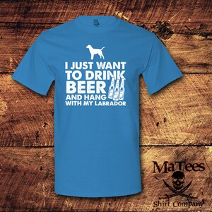 May include: A blue t-shirt with white text that reads "I just want to drink beer and hang with my labrador". The shirt also features a white silhouette of a labrador retriever and three white beer bottles.