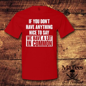 May include: A red t-shirt with the text "IF YOU DON'T HAVE ANYTHING NICE TO SAY WE HAVE A LOT IN COMMON" in white block letters. The shirt also features the "MaTees" logo and "Shift Company" text.
