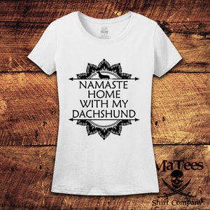 Op de afbeelding: Wit T-shirt met een zwart mandala-ontwerp en de tekst "Namaste Home With My Dachshund".
