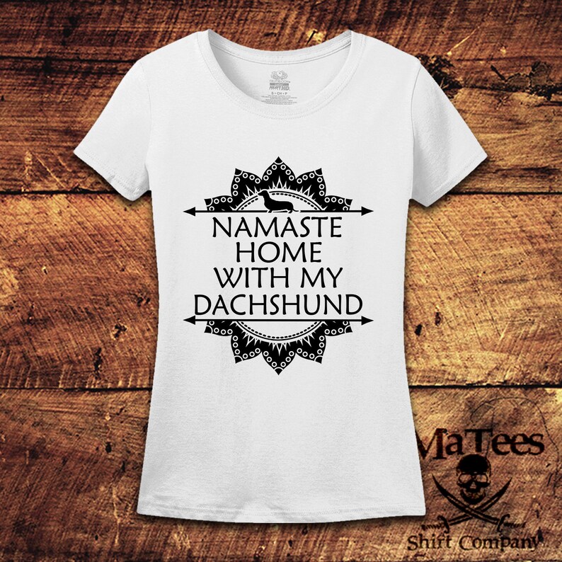 Op de afbeelding: Wit T-shirt met een zwart mandala-ontwerp en de tekst "Namaste Home With My Dachshund".