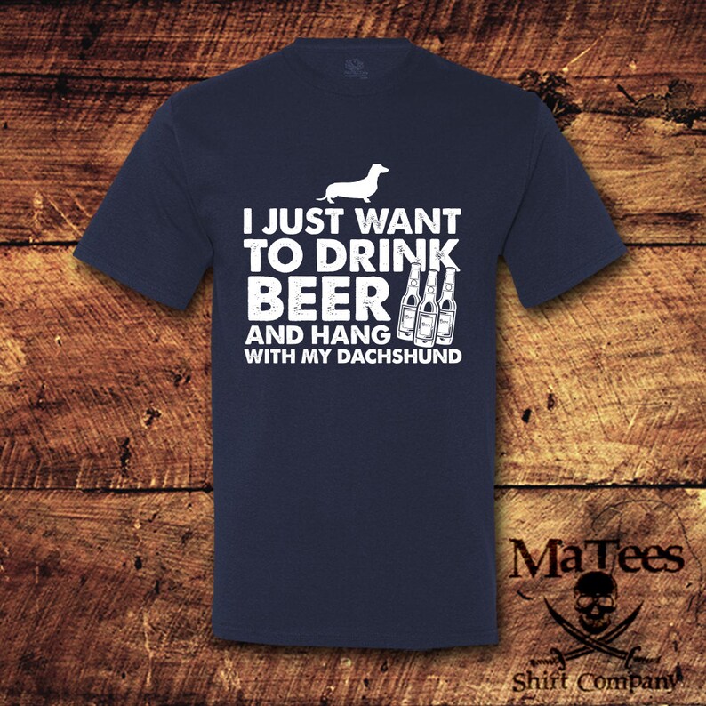 May include: A navy blue t-shirt with a white dachshund and the text "I just want to drink beer and hang with my dachshund".