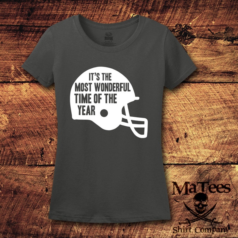 K&ouml;nnte beinhalten: Ein dunkelgraues T-Shirt mit einer wei&szlig;en Grafik eines Footballhelms und dem Text "Es ist die sch&ouml;nste Zeit des Jahres".