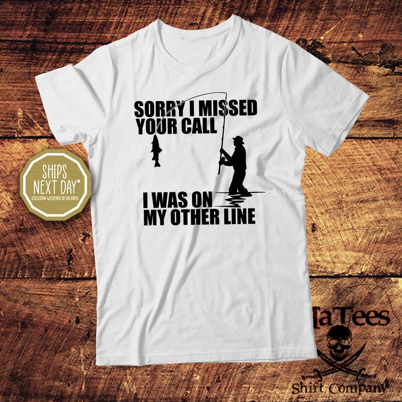 May include: White t-shirt with a black graphic of a fisherman and the text "SORRY I MISSED YOUR CALL I WAS ON MY OTHER LINE." The shirt also features a fish on the fishing line. The shirt is from the "Shirt Company".