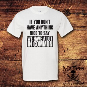 May include: White t-shirt with the text "IF YOU DON'T HAVE ANYTHING NICE TO SAY WE HAVE A LOT IN COMMON" in black. The shirt has short sleeves and a crew neck. The MaTees logo is in the bottom right corner.