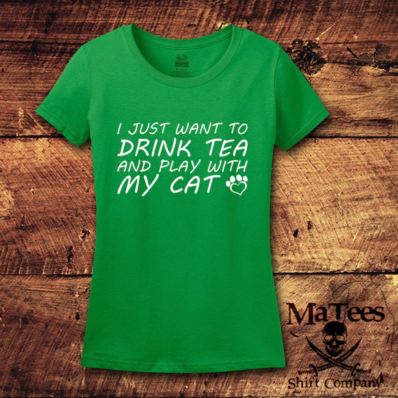 May include: Green t-shirt with white text that reads "I just want to drink tea and play with my cat" with a paw print and heart symbol.