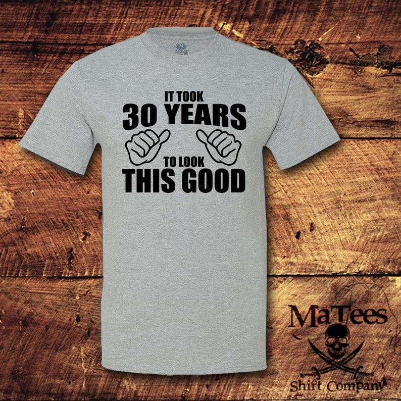 May include: Gray t-shirt with black text that reads "It took 30 years to look this good". The text is accompanied by two black thumbs up symbols.