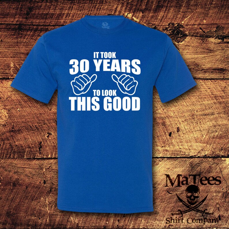May include: A royal blue t-shirt with white text that reads "It took 30 years to look this good". The text is accompanied by two white thumbs up symbols.