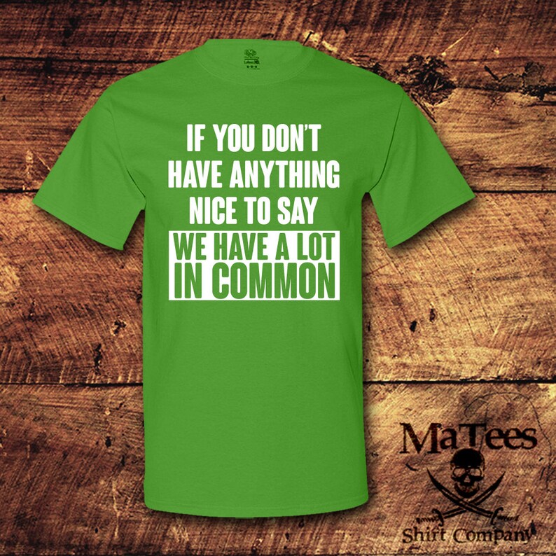 May include: A bright green t-shirt with the text "IF YOU DON'T HAVE ANYTHING NICE TO SAY WE HAVE A LOT IN COMMON" in white. The shirt also features the MaTees logo and "Shift Company" text.