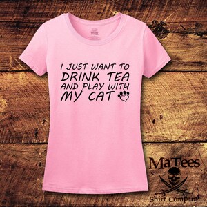 May include: Pink t-shirt with black text that reads "I just want to drink tea and play with my cat" with a paw print and heart graphic.