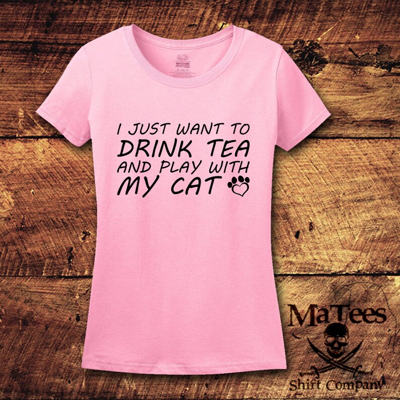 May include: Pink t-shirt with black text that reads "I just want to drink tea and play with my cat" with a paw print and heart graphic.