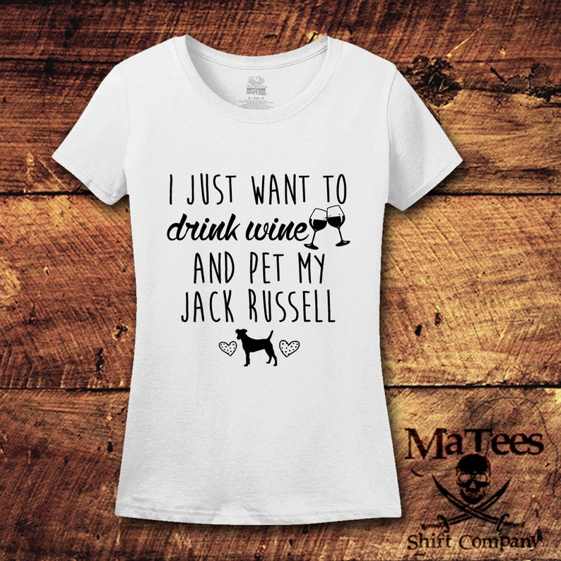 May include: White t-shirt with black text that reads "I just want to drink wine and pet my Jack Russell". The text is accompanied by a graphic of two wine glasses and a Jack Russell terrier.