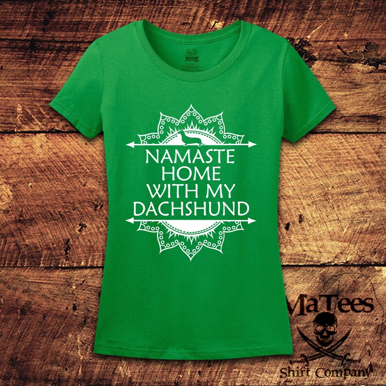 Op de afbeelding: Groen T-shirt met een wit mandala-ontwerp en de tekst "Namaste Home With My Dachshund".