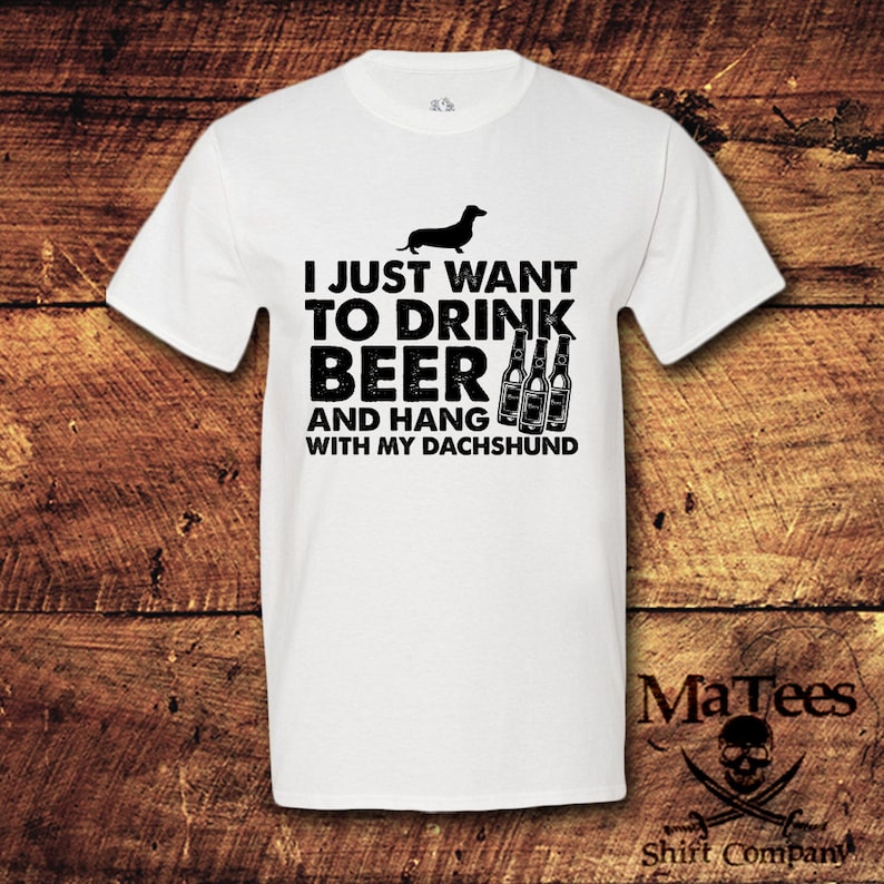 May include: White t-shirt with a black dachshund silhouette and the text "I just want to drink beer and hang with my dachshund".
