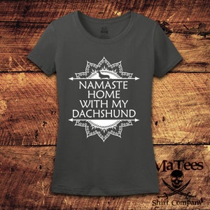 Op de afbeelding: Een donkergrijs T-shirt met een wit mandala-ontwerp en de tekst "Namaste Home With My Dachshund".