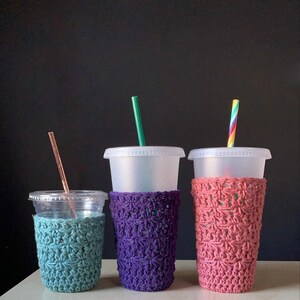 Peut inclure: Trois manchons &agrave; caf&eacute; en crochet de diff&eacute;rentes couleurs&nbsp;: sarcelle, violet et rose. Les manchons sont r&eacute;alis&eacute;s avec un motif de point simple et sont con&ccedil;us pour s&rsquo;adapter aux tasses de taille standard.