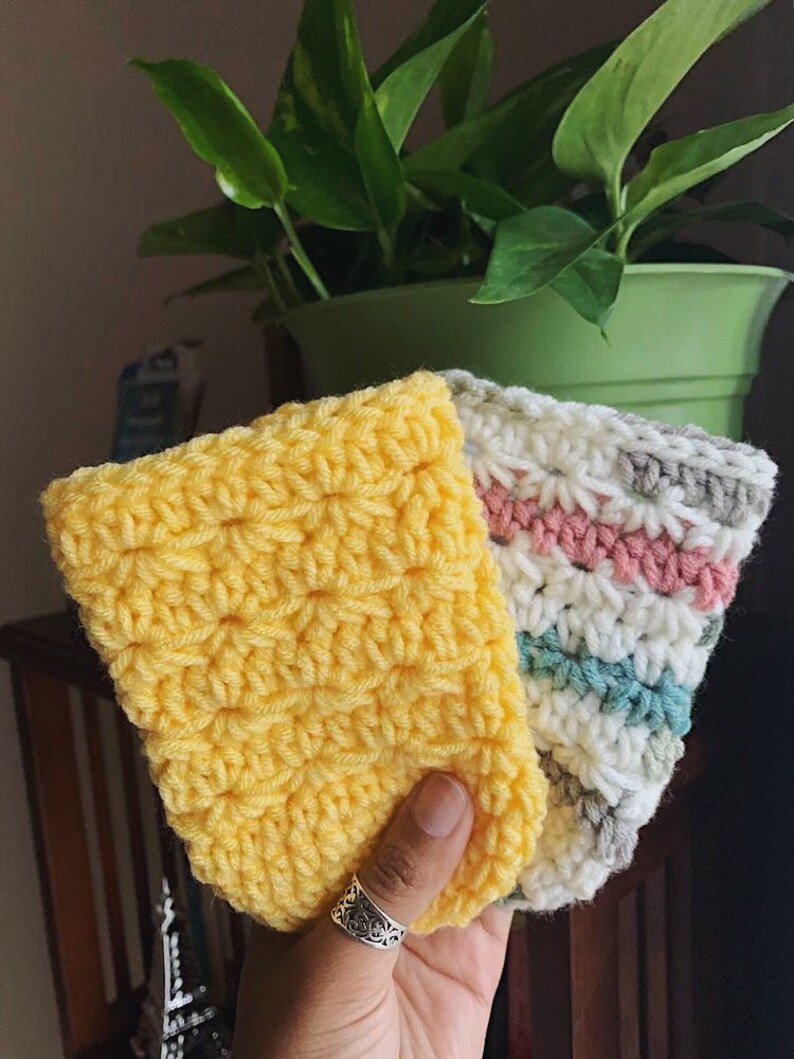 Peut inclure: Trois manchons &agrave; caf&eacute; en crochet de couleur jaune, blanc, gris, rose et bleu. Les manchons sont faits avec un point textur&eacute;.