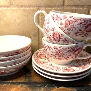 May include: A set of four vintage teacups and saucers with a pink floral pattern. The cups and saucers are stacked on top of each other.