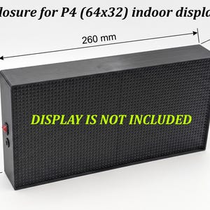 以下が含まれることがあります： P4 64x32屋内ディスプレイ用の黒い長方形の筐体で、サイズは260mm x 132mm x 50mmです。側面には赤い電源スイッチがあり、Enclosure for P4 (64x32) indoor displayおよびDISPLAY IS NOT INCLUDEDというテキストが記載されています。