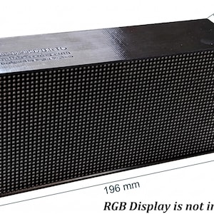 May include: A black rectangular electronic display housing with a grid-patterned front panel. The top surface features the text SCOREDUINO, buildcircuit.com, and Designed by Build Circuit. It measures 196 mm by 100 mm by 50 mm, with a red power switch.