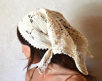 May include: Cream-colored crochet head covering with a decorative dragonfly pattern. The head covering is tied at the nape of the neck and has a scalloped edge. The head covering is made of a soft, open-weave material.
