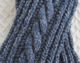 May include: Close-up of a blue and white knitted scarf with a cable knit design. The scarf is made of a soft, textured yarn and has a thick, warm appearance. The cable knit pattern adds visual interest and a classic touch to the scarf.