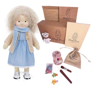May include: A handmade doll with blonde curly hair, wearing a light blue dress, a beige knit cardigan, a blue scarf, and white shoes. Included are a brown box, a small white bear keychain, a sewing kit, a drawstring bag, and hair accessories.